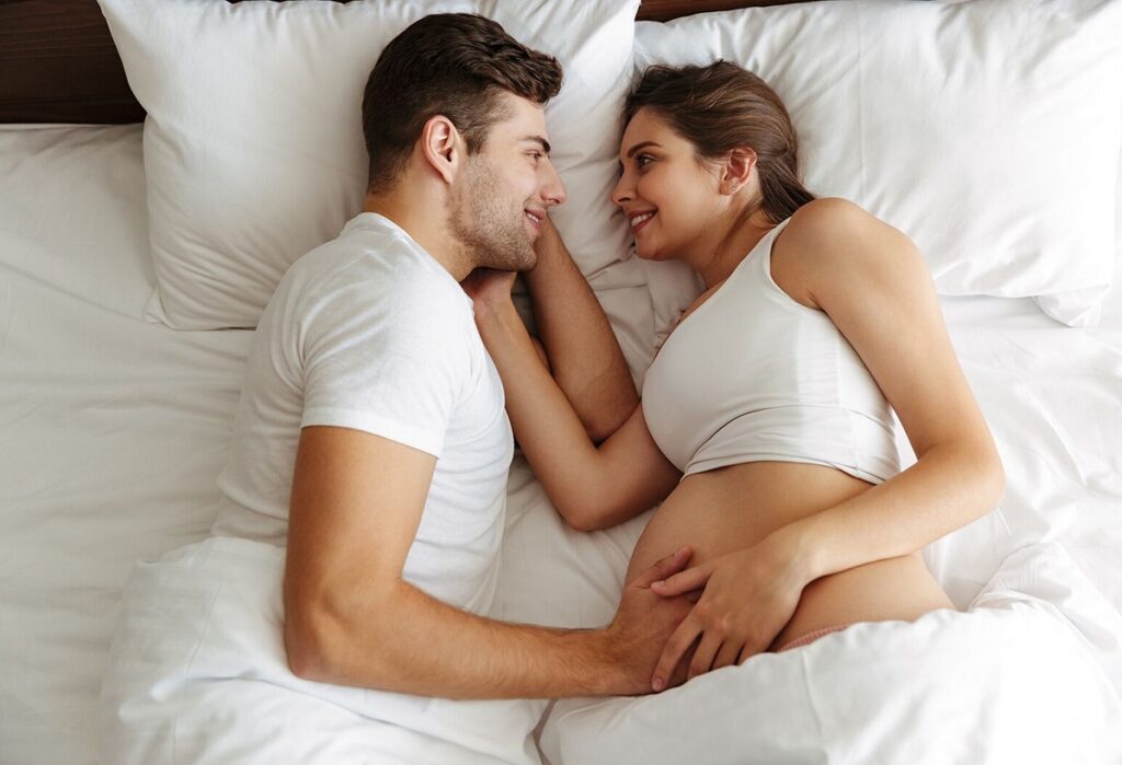 Coppia a letto si prepara a coniugare sesso e gravidanza