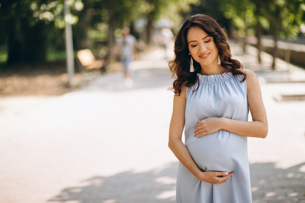 donna in stato di gravidanza passeggia accarezzandosi pancia