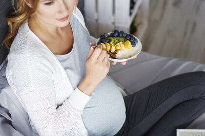 celiachia in gravidanza, donna mangia frutta sul letto